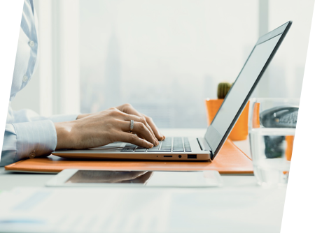 Birou modern, luminos: lucru pe laptop lângă fereastră cu vedere urbană.